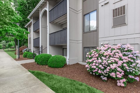 a building with a sidewalk and flowers in front of it