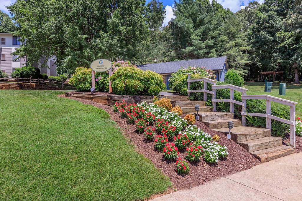 a garden with stairs and flowers in front of a house