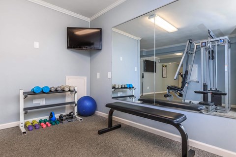 a gym with a mirror and exercise equipment and a television
