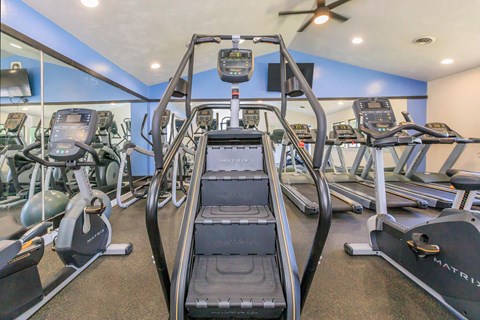 a gym with cardio equipment and a ceiling fan