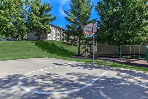 a basketball court in front of a building with trees