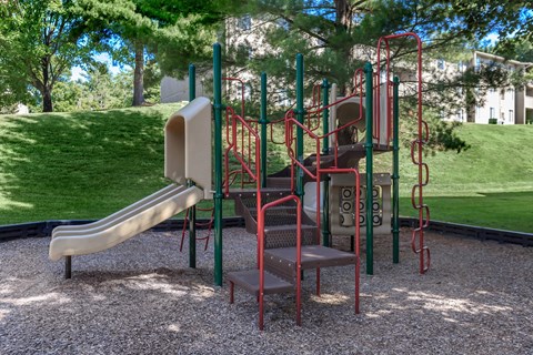 a playground with a slide and chairs in a park