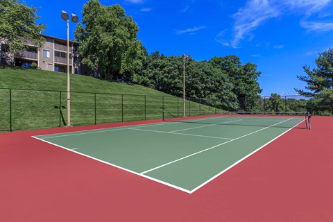 a tennis court with trees and a building in the background