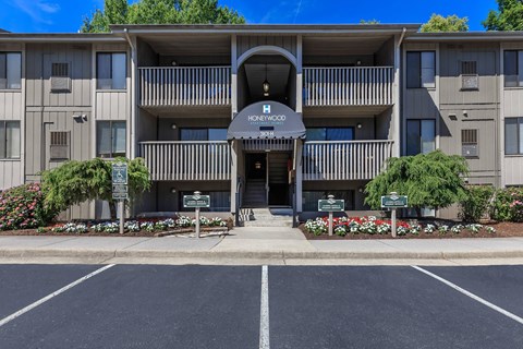 the front entrance of a building with a driveway and flower beds