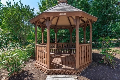 a gazebo with a bench in a garden