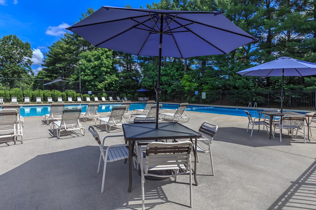 a patio with tables and umbrellas next to a swimming pool