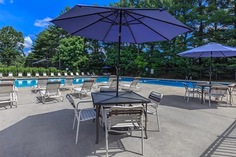 a patio with tables and umbrellas next to a swimming pool