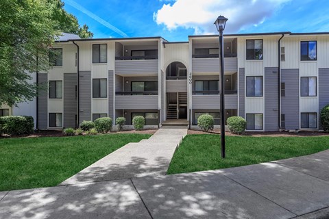 an exterior view of an apartment building with a sidewalk and grass