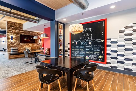 a dining room with a table and chairs and a chalkboard on the wall