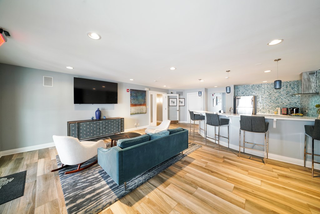 A living room with a blue couch and a television on the wall.