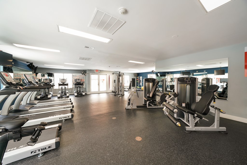 A gym with a variety of equipment including treadmills, weights, and exercise machines.