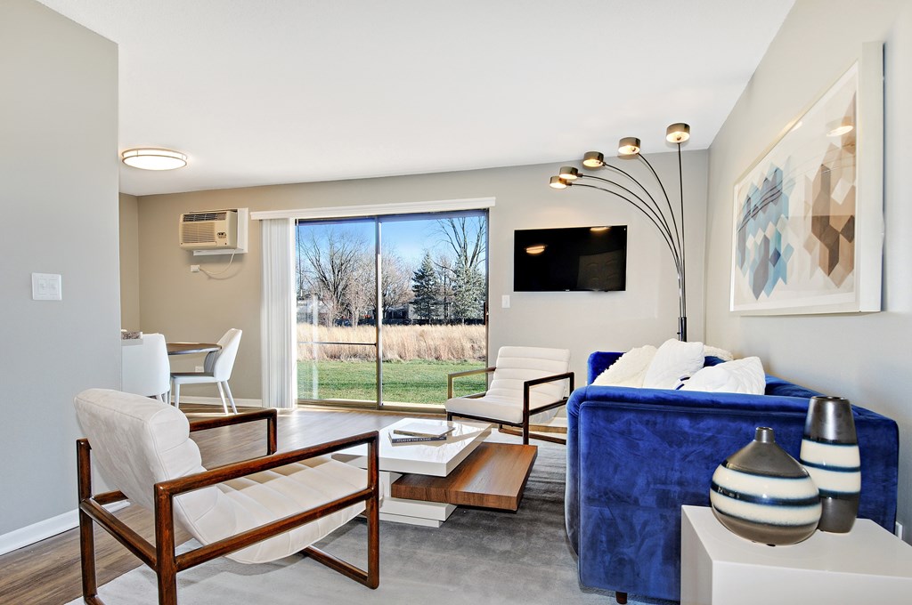 A living room with a blue couch and a wooden chair.