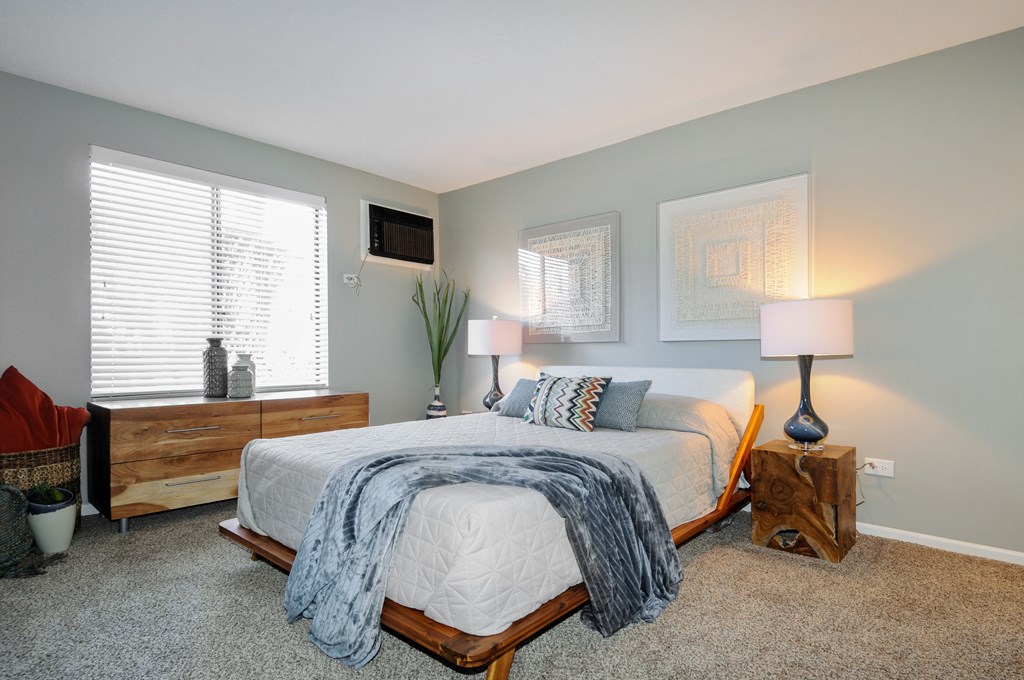 A bedroom with a bed, nightstands, and a window.