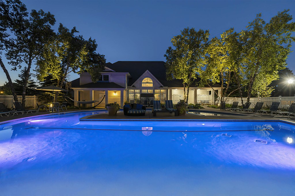a swimming pool at night with a house in the background