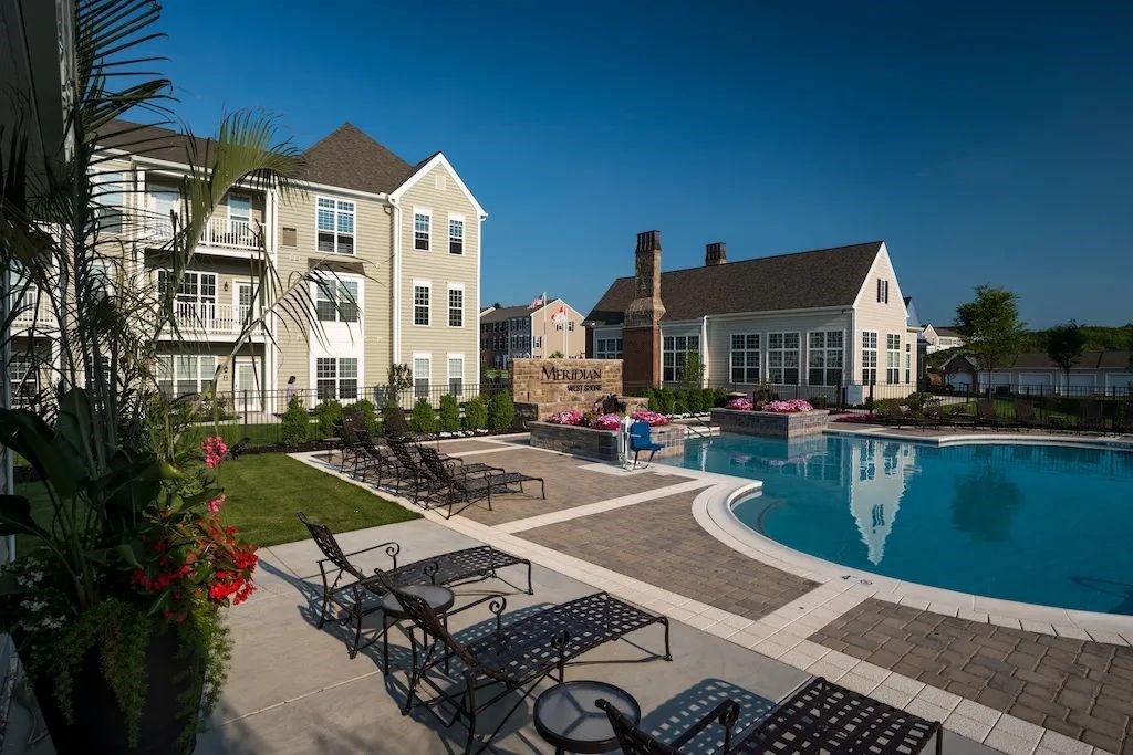 A pool area with lounge chairs and a building in the background.at Meridian West Shore, Mechanicsburg Pennsylvania