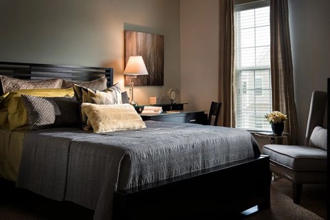 A bedroom with a large bed and a chair.