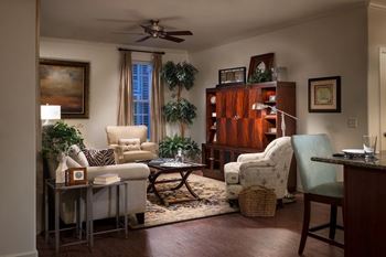 A living room with a white chair, a brown table, and a ceiling fan.at Meridian West Shore, Pennsylvania 17055