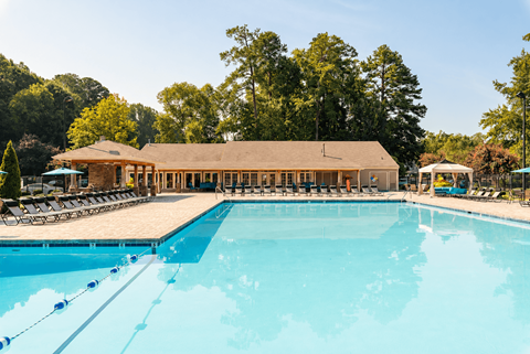 A large swimming pool in front of a building surrounded by trees.