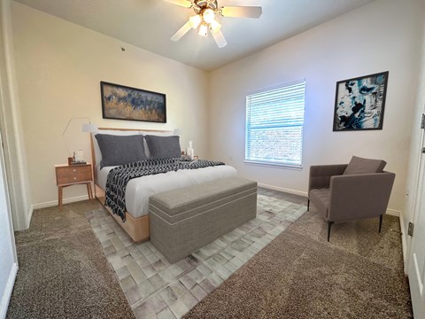 a bedroom with a bed and a chair and a ceiling fan