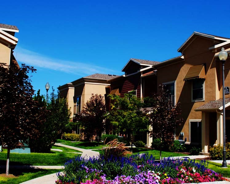 Liberty Landing Apartments flower bed with walking trails outside tan buildings. West Jordan, Utah.