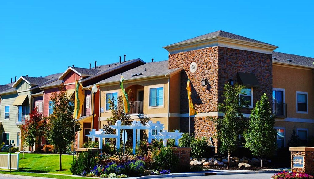 Liberty Landing Apartments entrance with flower beds and white wooden decorative structure. West Jordan, Utah.