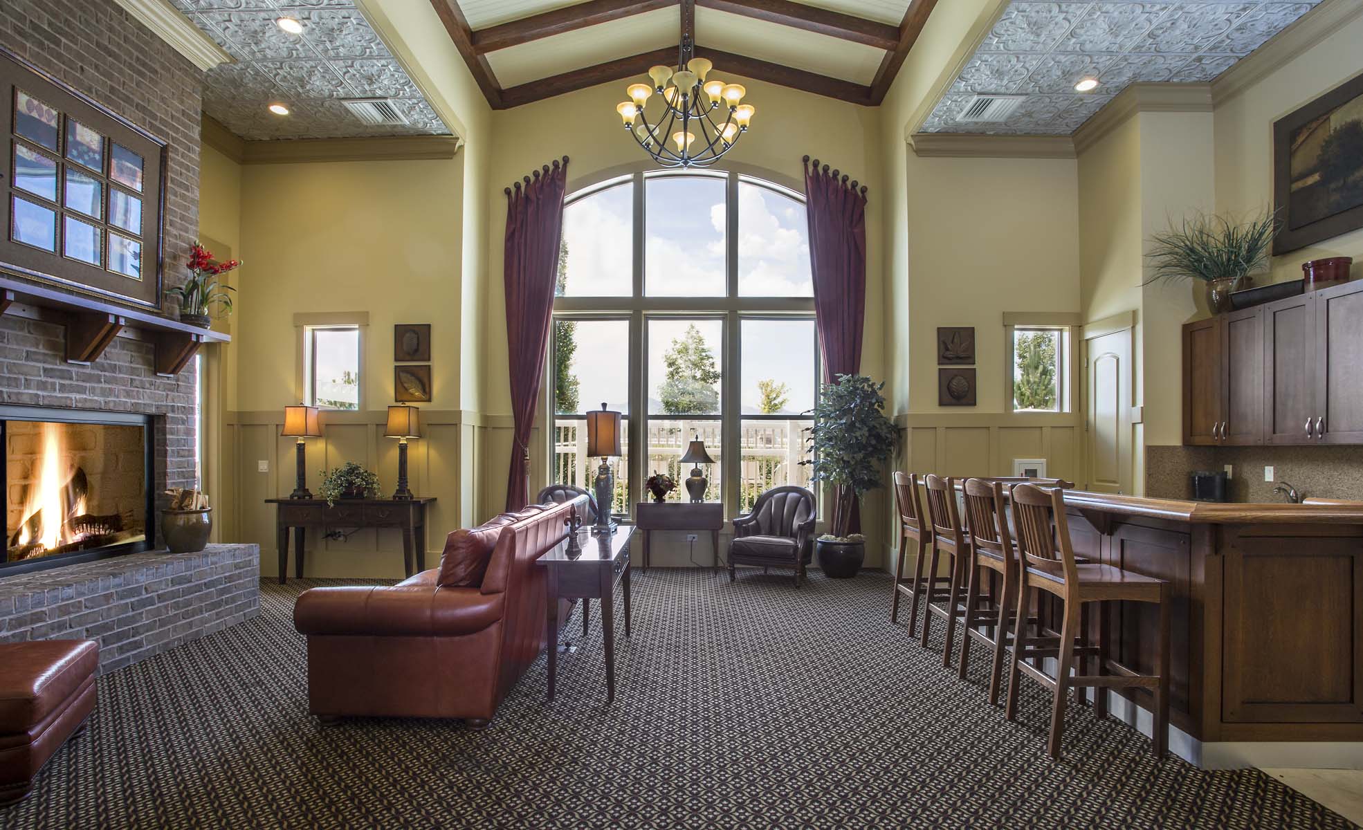 Liberty Landing Apartments large clubhouse with a fireplace, leather couches, bar seating and a large window