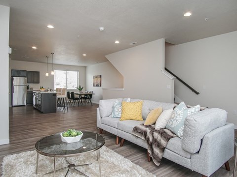 A modern living room with a grey couch and a glass coffee table.