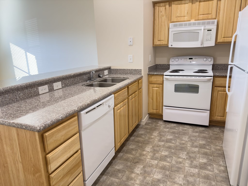 Liberty Bend Townhome Apartments, Sandy, Utah kitchen with white appliances and granite counter tops and wooden cabinets