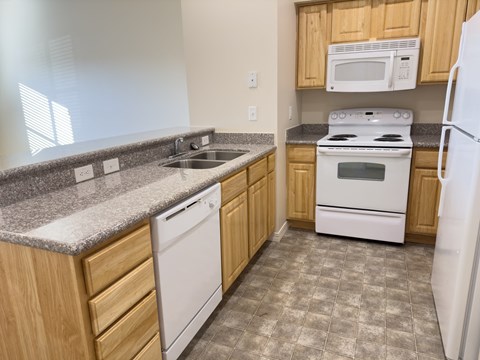 a kitchen with white appliances and granite counter tops and wooden cabinets