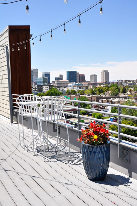 A patio with a table and chairs overlooking a city skyline.