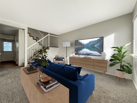 A living room with a blue couch, a wooden coffee table, a staircase, and a large painting on the wall.