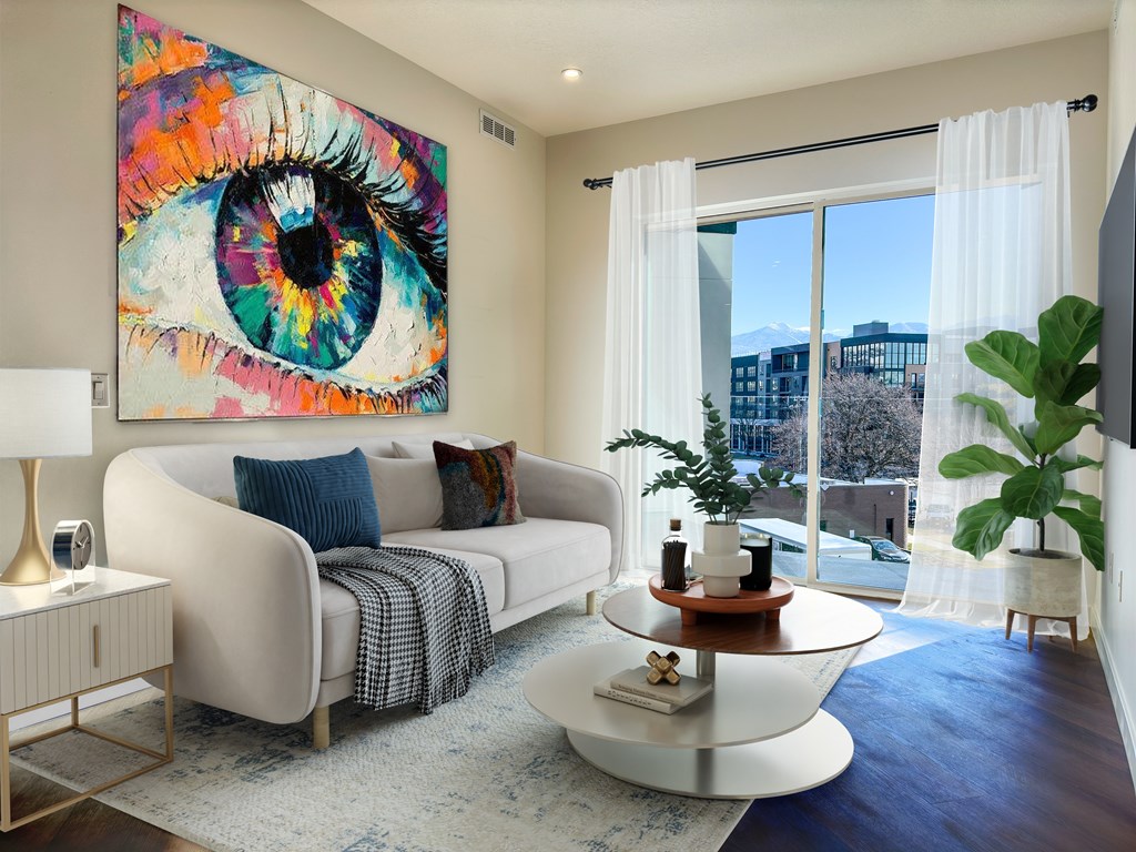 Liberty Duet Apartments, Salt Lake City, Utah; A living room with a large eye painting on the wall, sliding glass doors, white sofa.