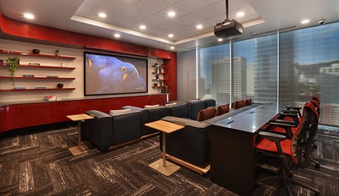 A conference room with a large screen and comfortable seating.