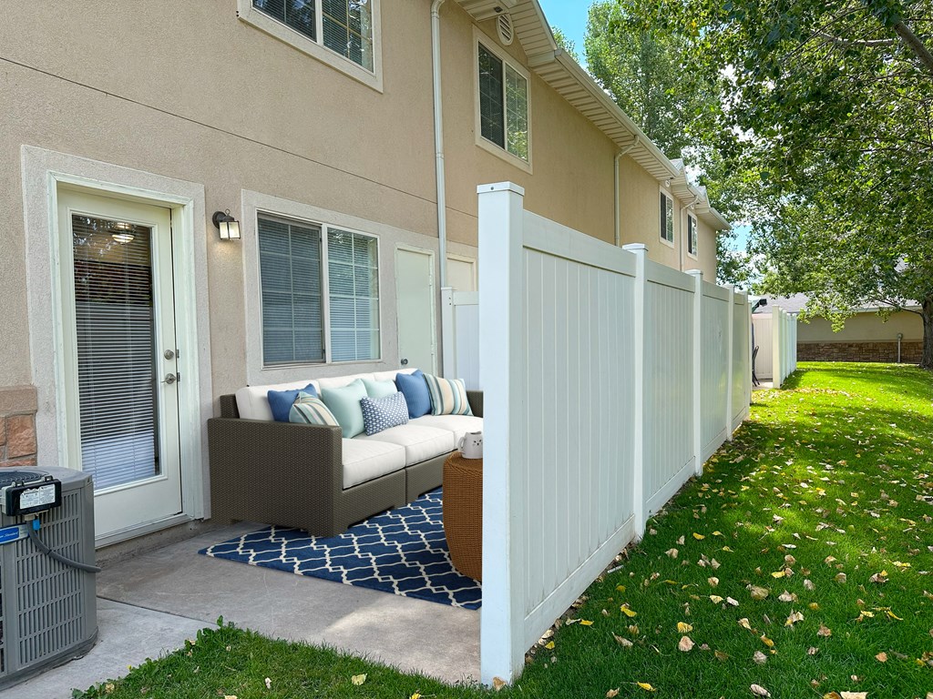 The Ridge at Jordan Landing Apartments, West Jordan, Utah, a patio with an outdoor couch in front of an apartment/townhome.