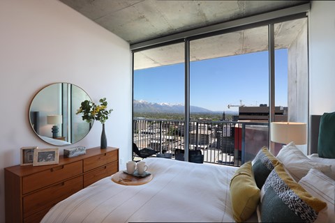 a bedroom with a bed and a view of the city and mountains