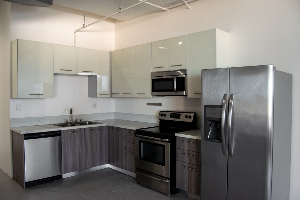 an empty kitchen with stainless steel appliances and white cabinets at Binford Lofts Apartments, Los Angeles , CA