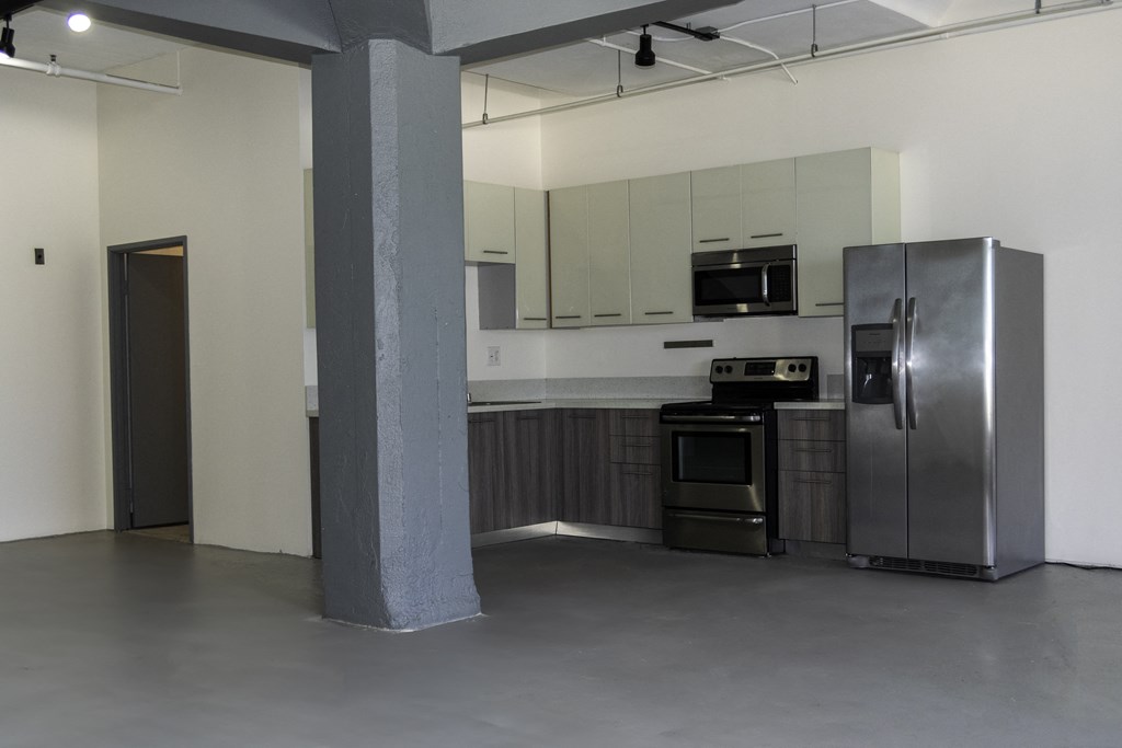 an empty kitchen with stainless steel appliances and a refrigerator at Binford Lofts Apartments, Los Angeles , CA, 90013