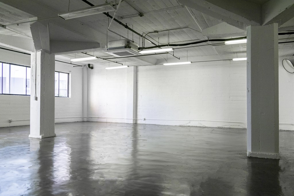 a large empty room with white walls and concrete floors at Binford Lofts Apartments, Los Angeles 