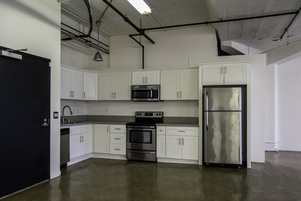 an empty kitchen with white cabinets and stainless steel appliances at Binford Lofts Apartments, Los Angeles , 90013