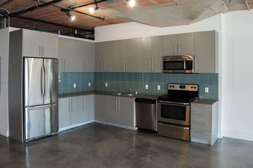 an empty kitchen with stainless steel appliances and gray cabinets at Binford Lofts Apartments, Los Angeles , CA, 90013