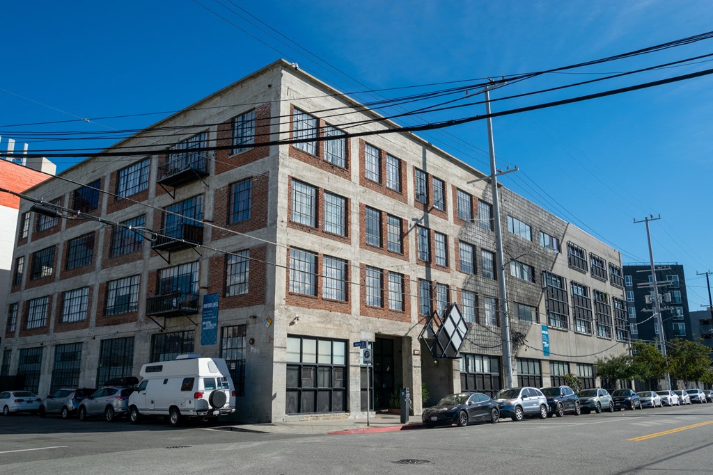 a large brick building with cars parked in front of it on a city street at Binford Lofts Apartments, California, 90013