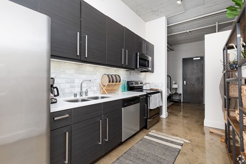 A kitchen with black cabinets and a white fridge.