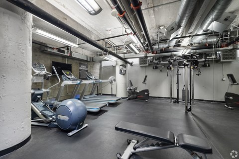 A gym with a variety of equipment including treadmills, exercise balls, and weight machines.