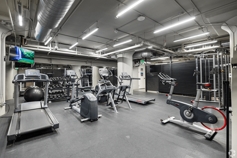 A gym with a variety of equipment including treadmills, weights, and exercise machines.