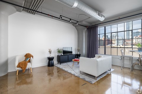 A living room with a white couch and a chair with a yellow blanket on it.