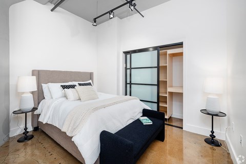 A bedroom with a large bed and a black bench.