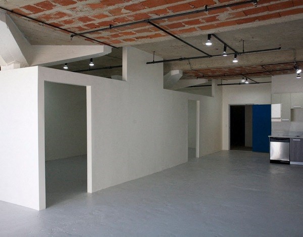 an empty room with white walls and a blue wall and a brick ceiling at Binford Lofts Apartments, Los Angeles , California