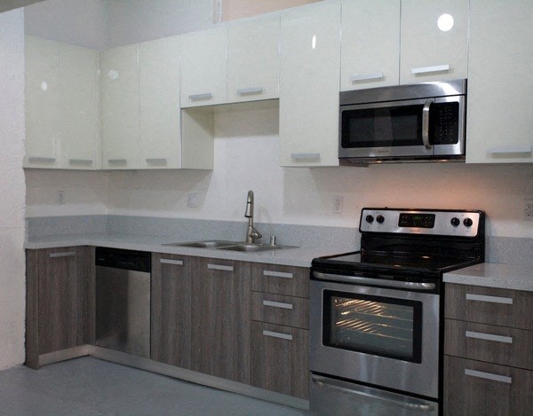 a kitchen with stainless steel appliances and white cabinets at Binford Lofts Apartments, California