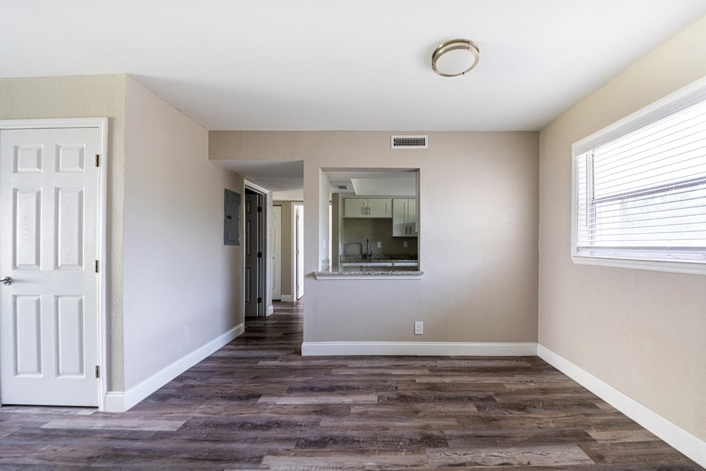an empty living room and hallway with a white door and a window at Palm Cove Apartments, Daytona Beach