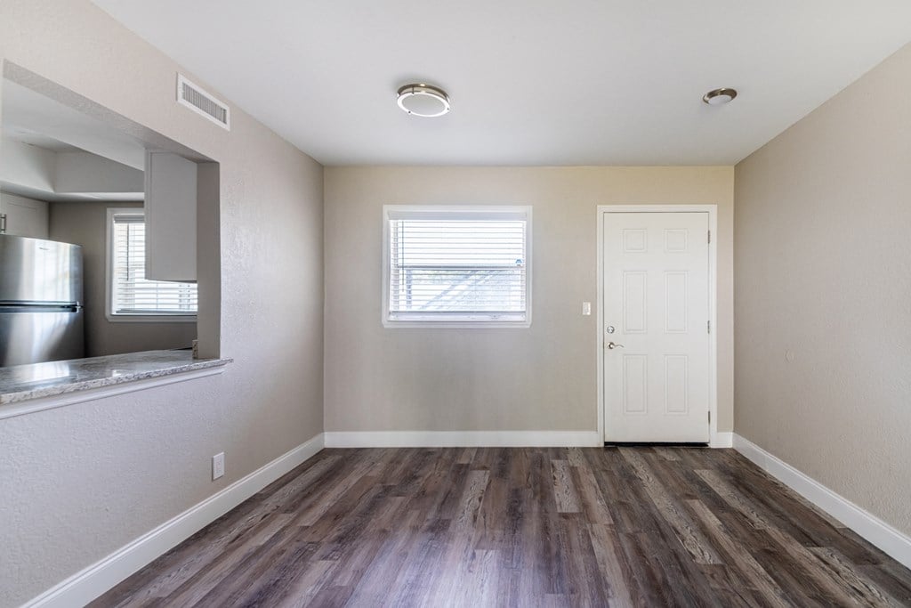 an empty living room with wood flooring and a door to the kitchen at Palm Cove Apartments, Daytona Beach, 32114